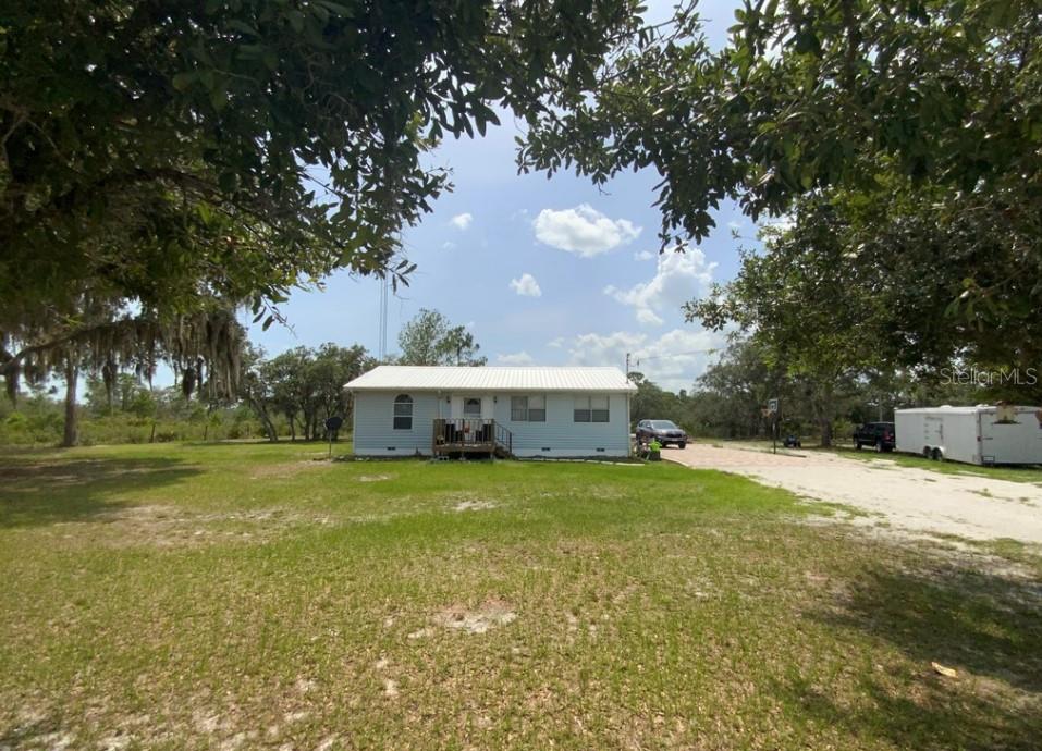 a view of a house with a yard and large trees