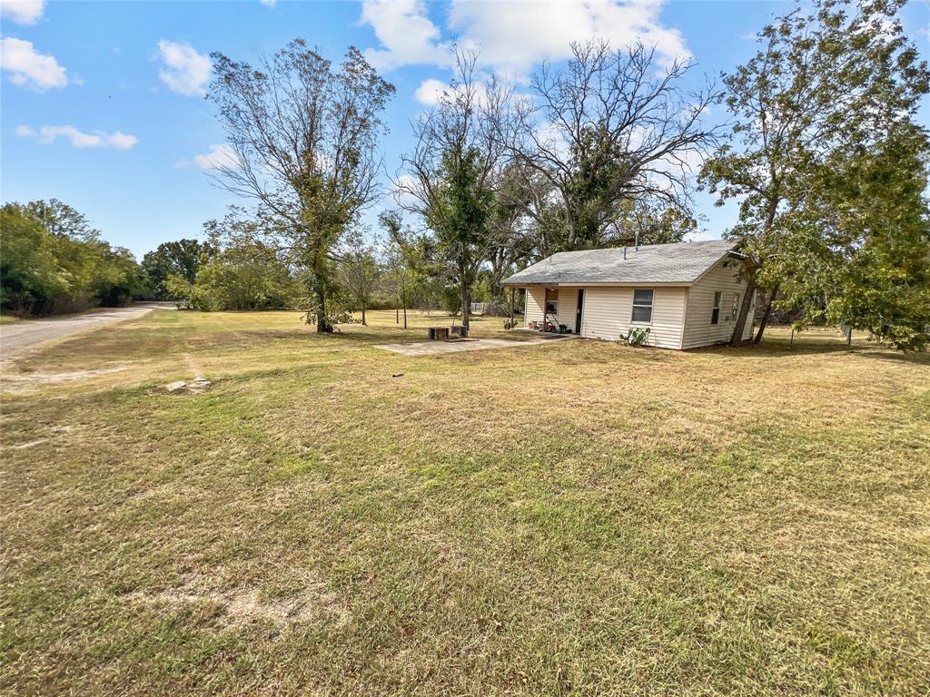 a view of house with yard and trees in the background