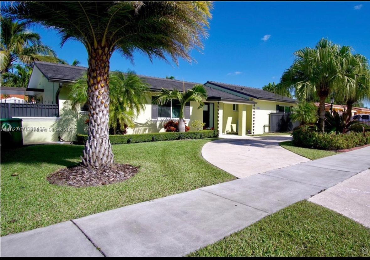 a front view of a house with a garden and tree