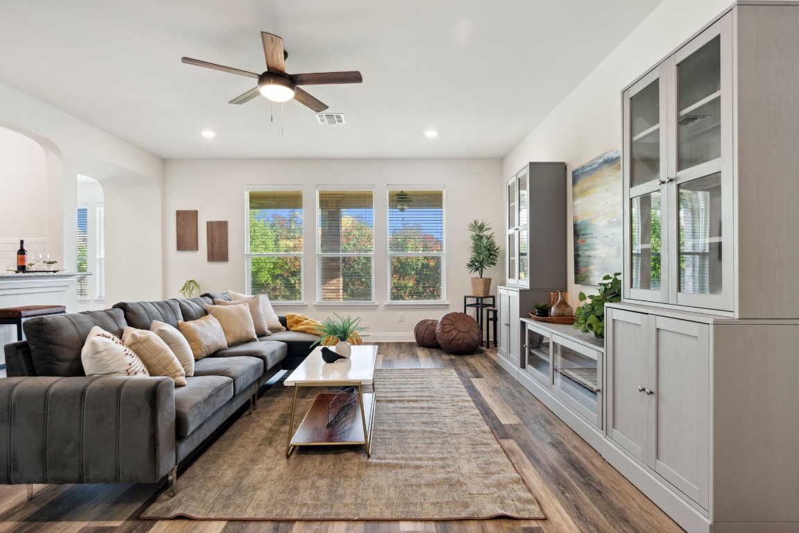 a living room with furniture ceiling fan and a large window