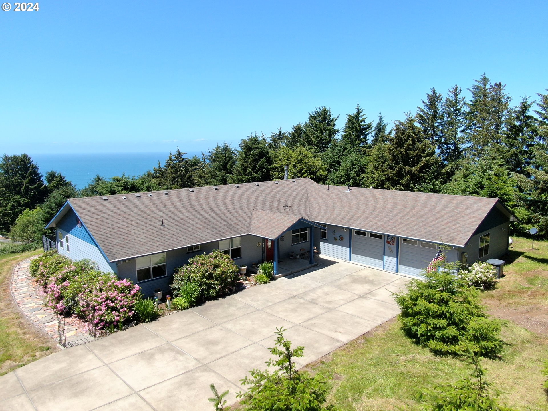 an aerial view of a house with yard and trees in the background