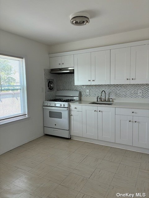 a kitchen with stainless steel appliances a white stove top oven and white cabinets