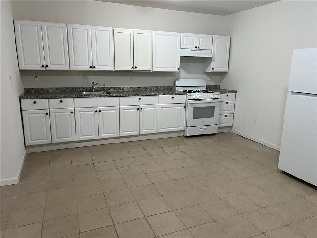 a kitchen with granite countertop white cabinets and white stainless steel appliances