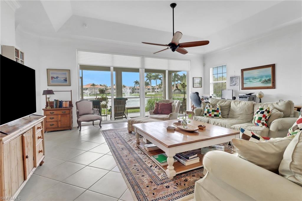 Tiled living room featuring a tray ceiling, crown molding, and ceiling fan