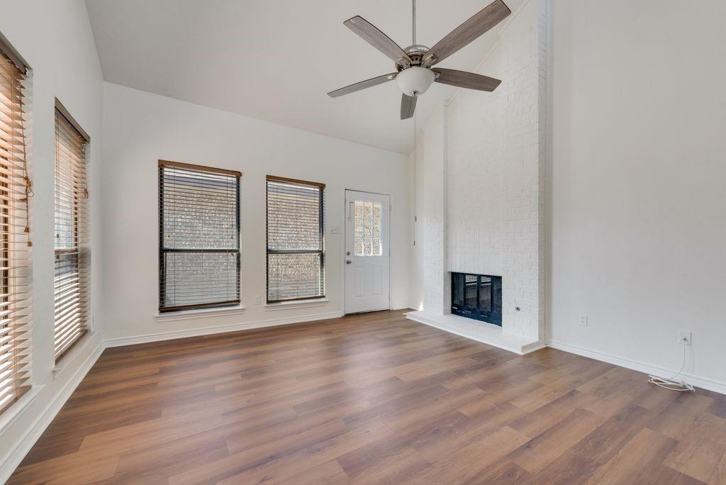 an empty room with wooden floor a ceiling fan and windows