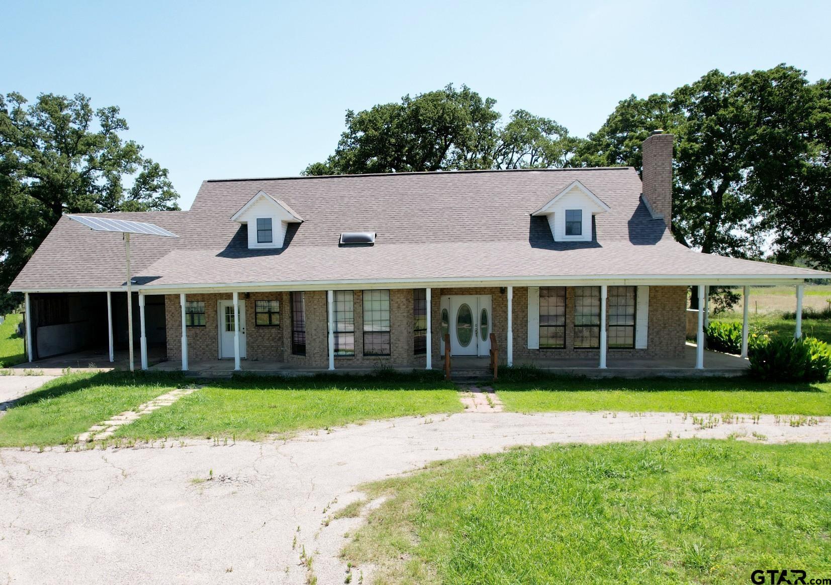 a view of a house with a yard and large tree