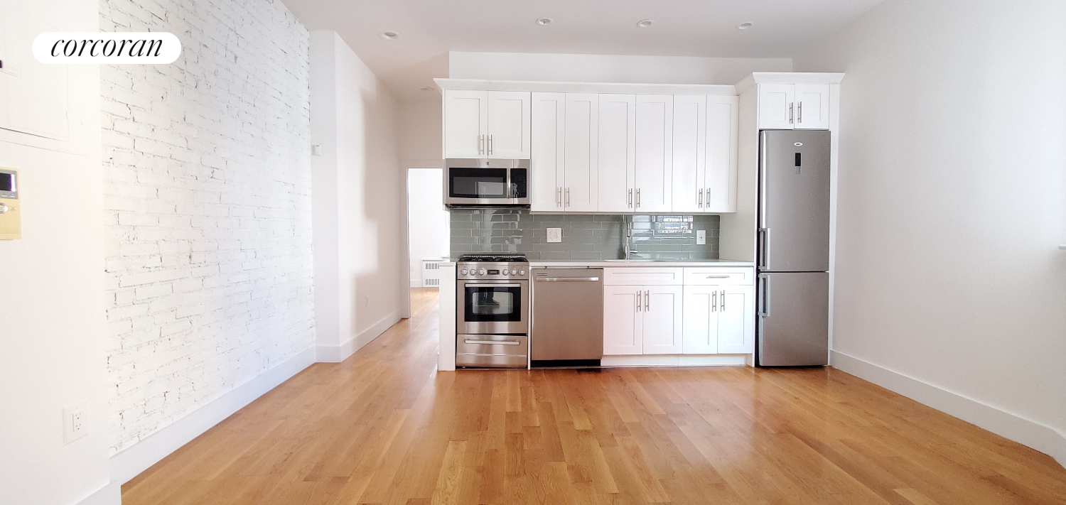 a kitchen with white cabinets and wooden floor