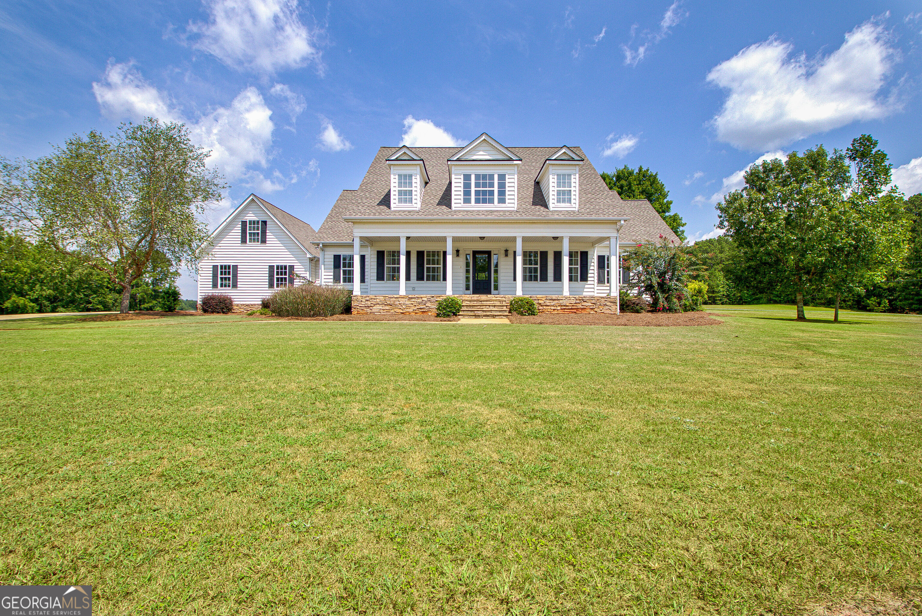 a front view of a house with a garden and trees