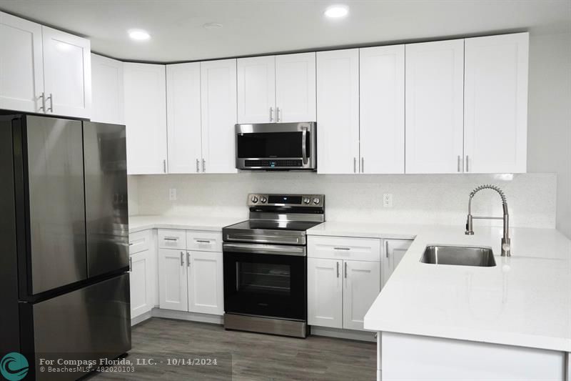 a kitchen with a refrigerator stove and white cabinets