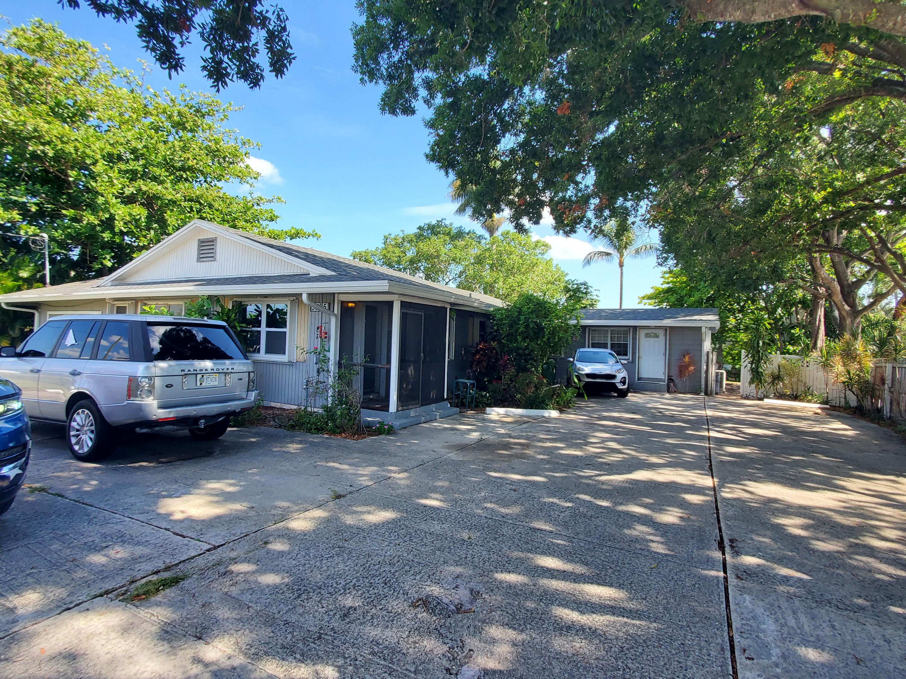 a front view of a house with a garden and trees