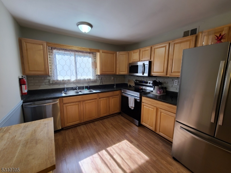 a kitchen with granite countertop a refrigerator stove top oven and sink