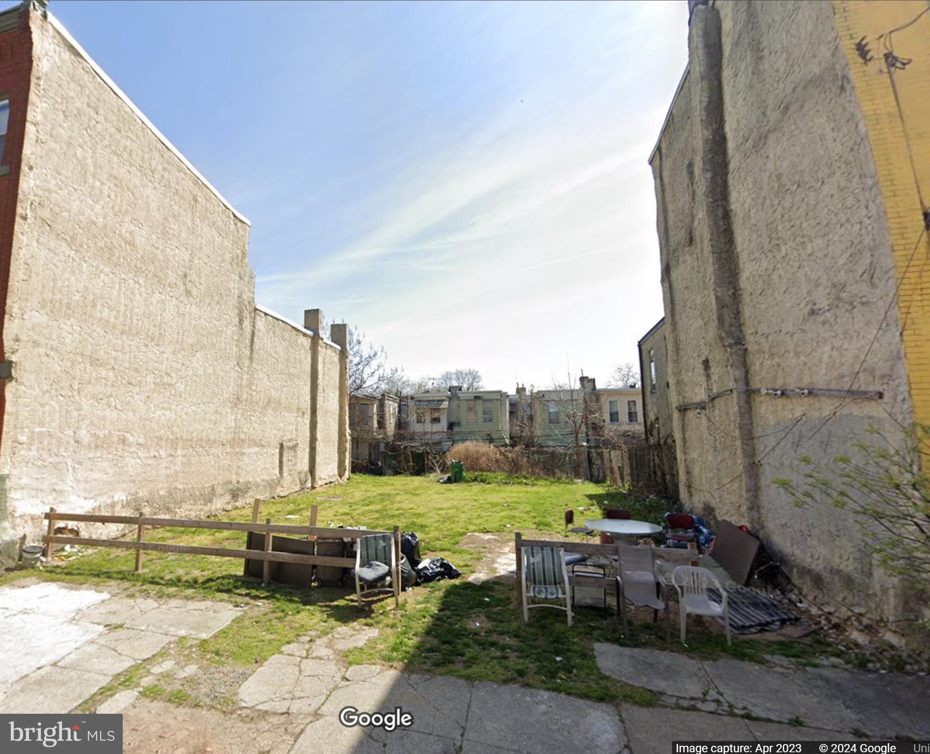 a view of a backyard with lawn chairs and iron fence