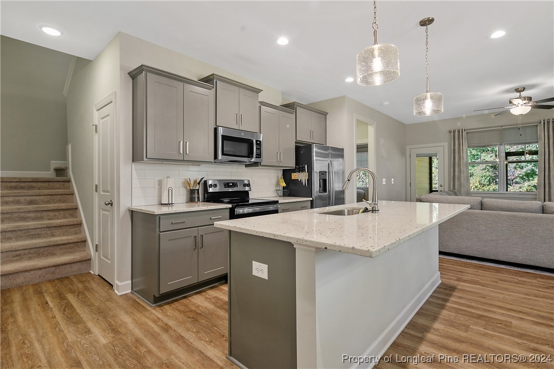 a kitchen with stainless steel appliances kitchen island granite countertop a sink and a stove top oven