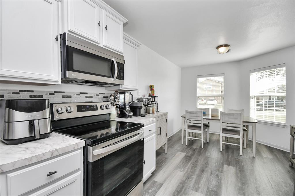 a kitchen with stainless steel appliances a stove a sink and white cabinets