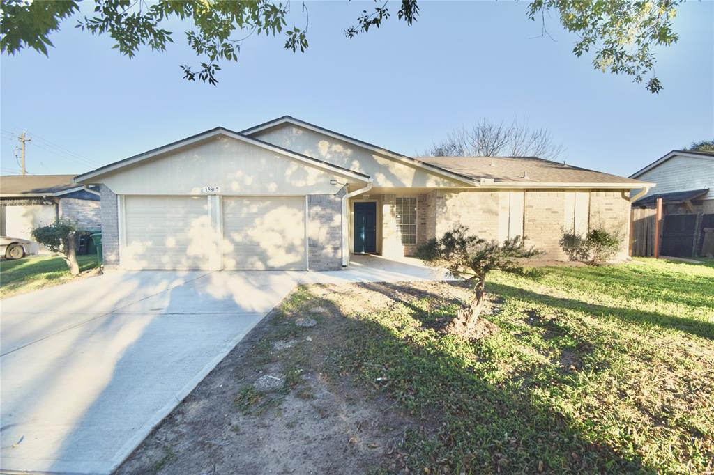 This is a single-story home with a two-car garage, a neat brick facade, and a modest front yard with young trees. The residence has a welcoming entrance with a covered porch area.