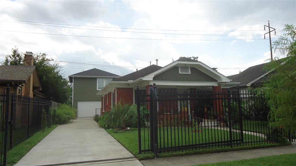 a view of a brick house with a small yard plants and large trees