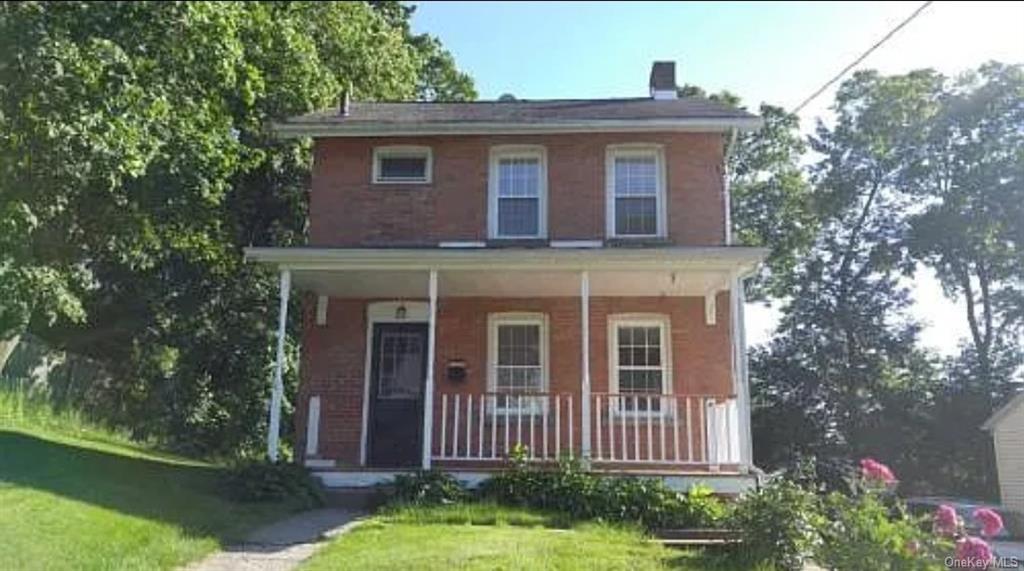 View of front of house featuring a front lawn and covered porch