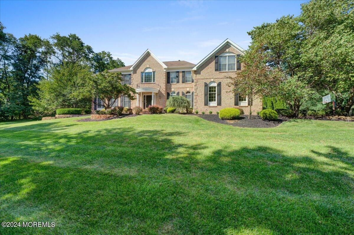 a view of a big house with a big yard and large trees