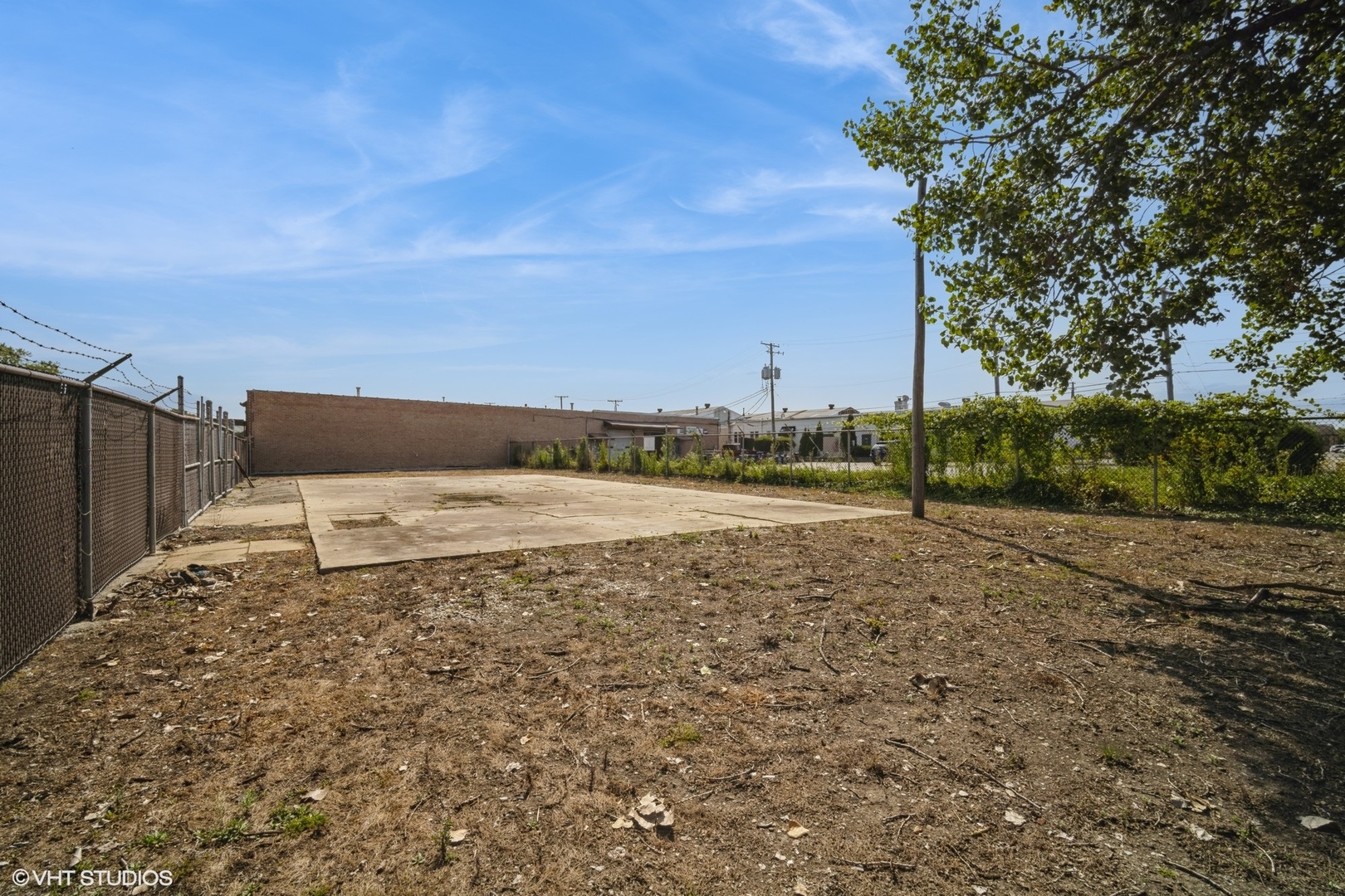 a view of a dry yard with wooden fence