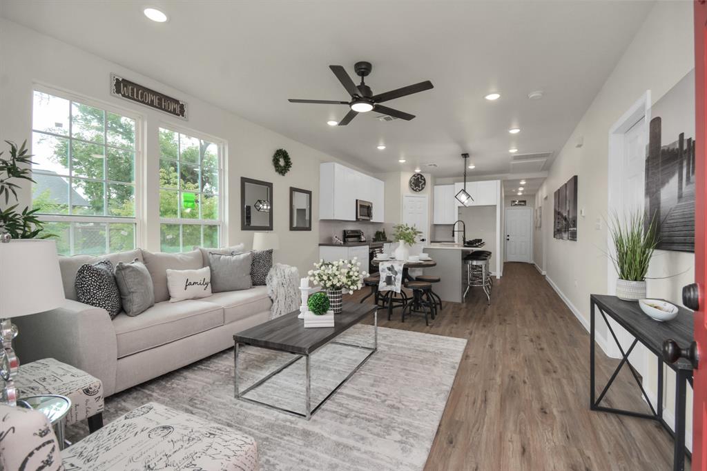 a living room with furniture kitchen view and a large window