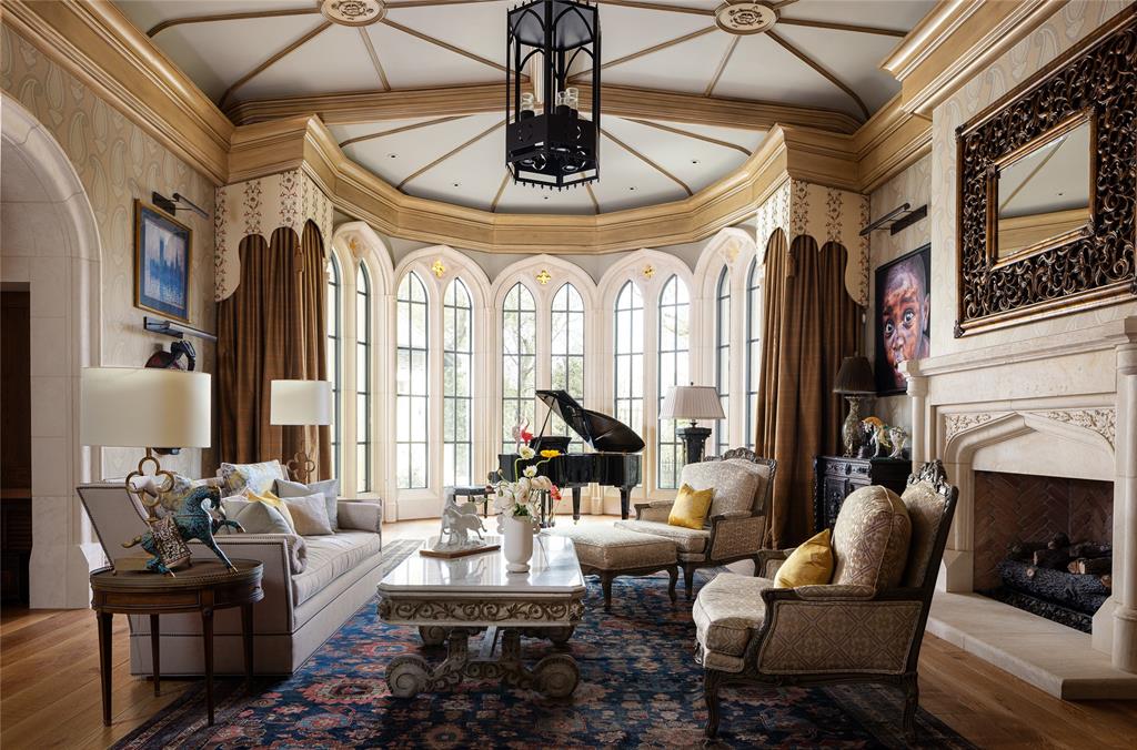 The formal living area is adorned with decorative deep crown molding, a custom iron lantern chandelier, portrait lighting, limestone gaslog fireplace and a coved ceiling with detailed rose accents