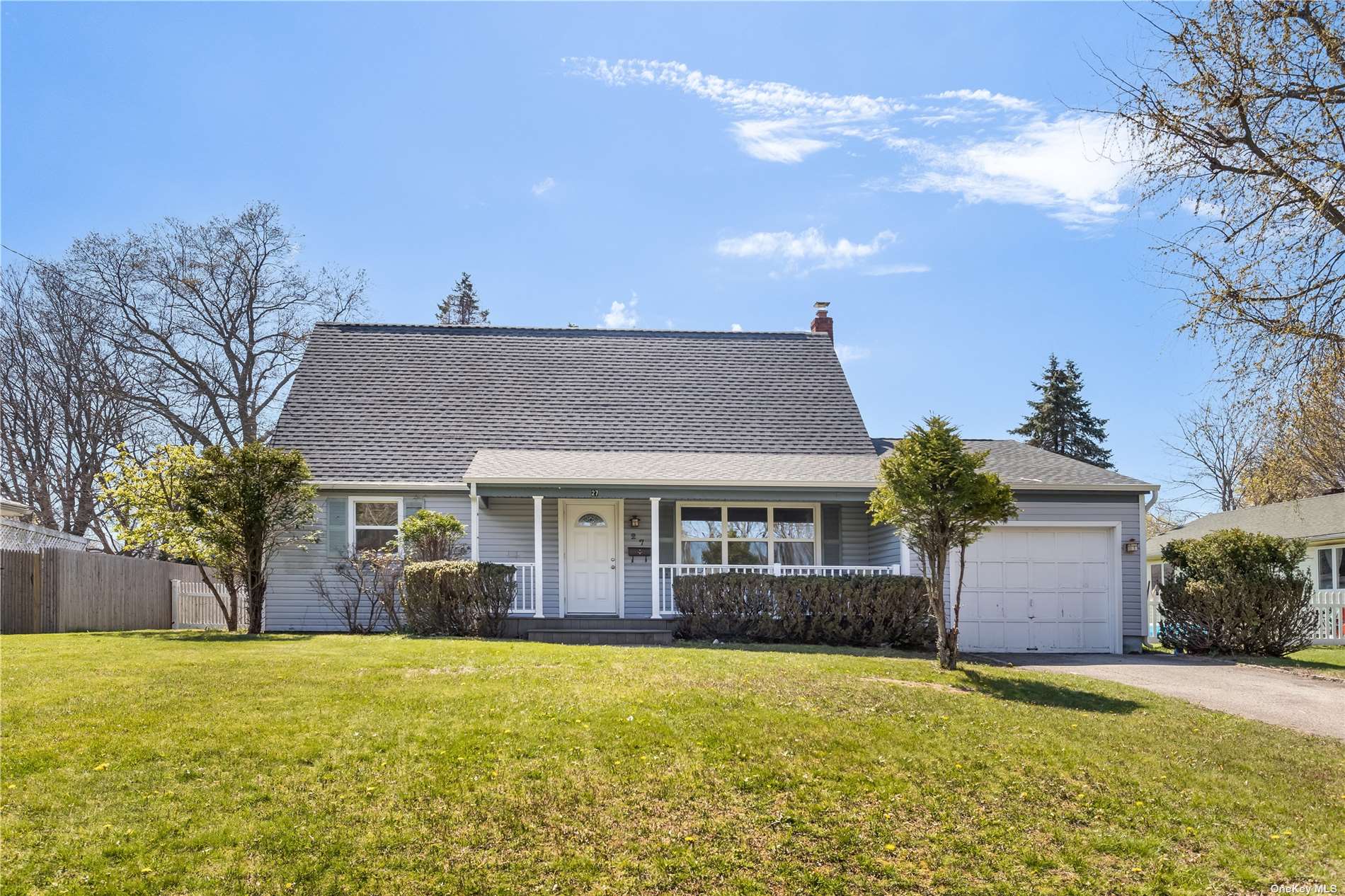 a front view of house with yard and trees in the background