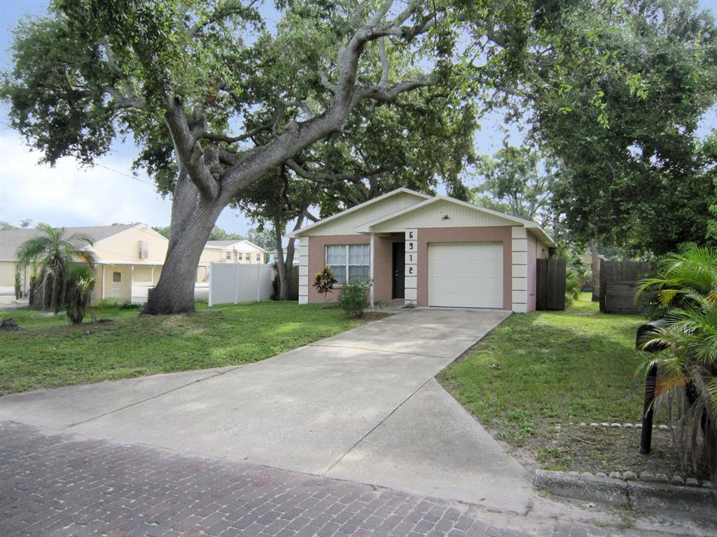 a front view of a house with a yard and large trees