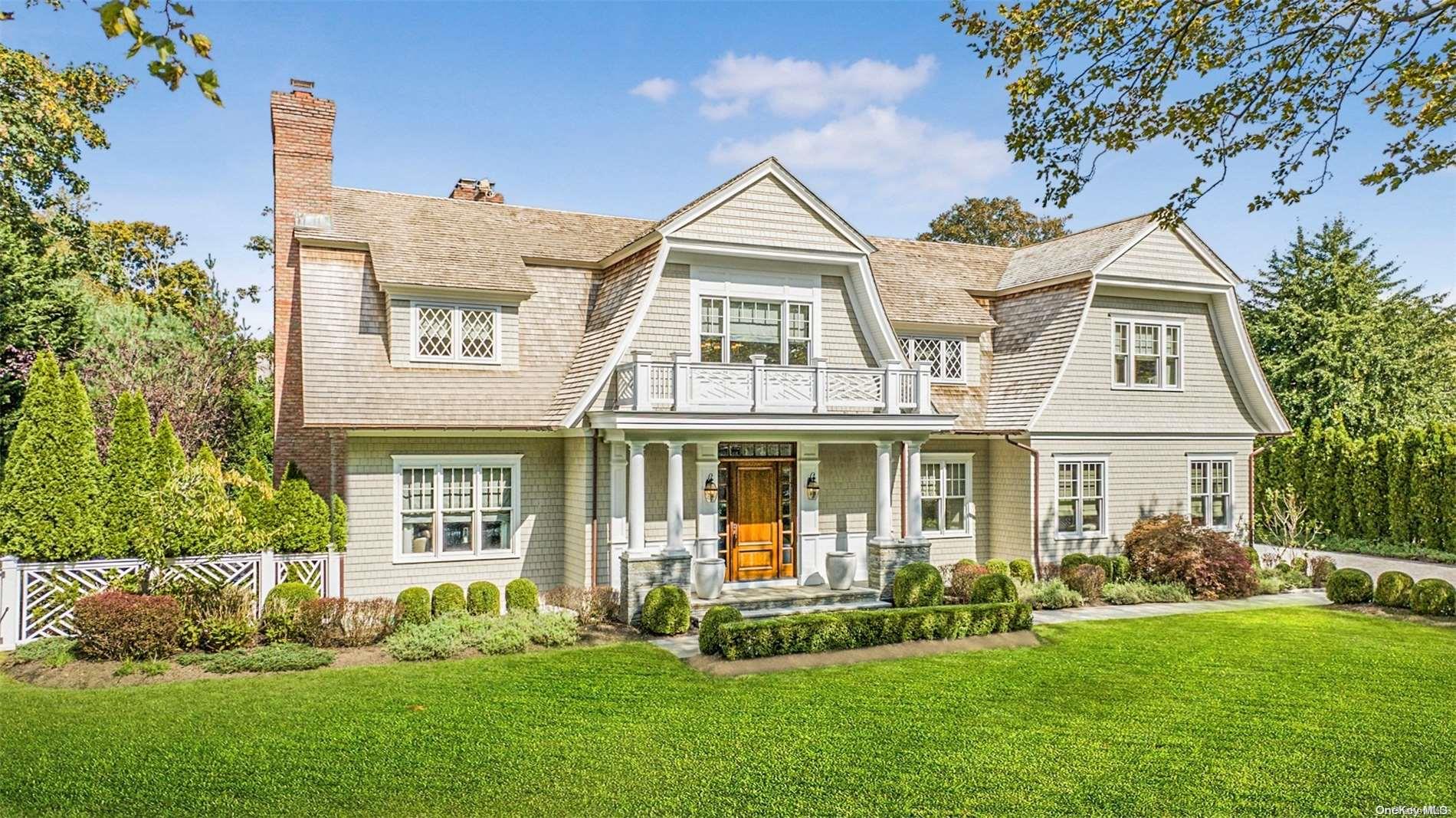 a view of a white house next to a yard with big trees