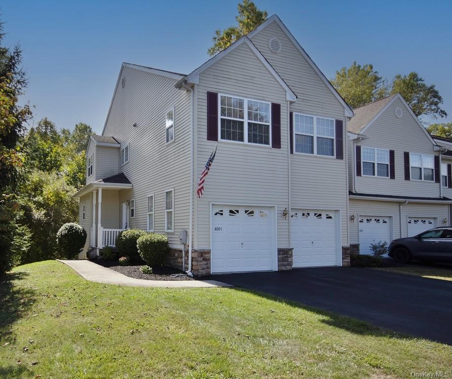 Front of townhouse and end unit featuring 2-car garage and front lawn