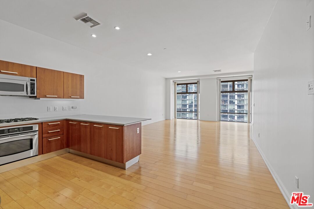 a kitchen with stainless steel appliances granite countertop a stove a sink and a refrigerator with wooden floor