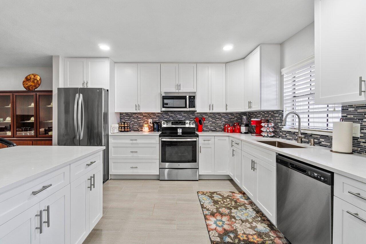 a kitchen with granite countertop a refrigerator stove and microwave