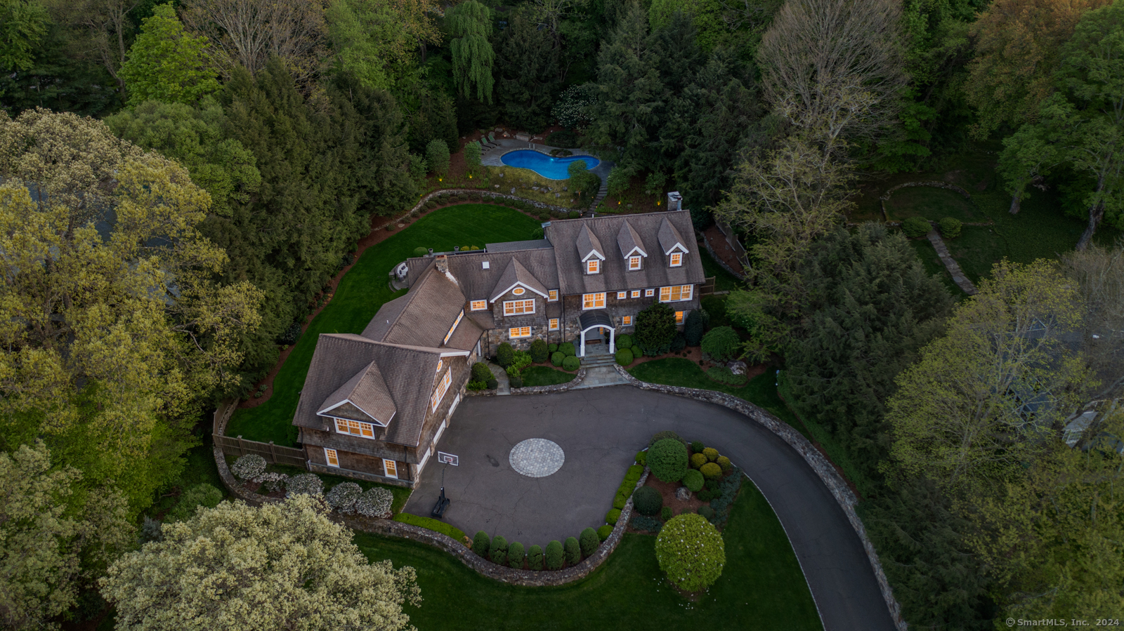 an aerial view of a house with outdoor space and trees all around