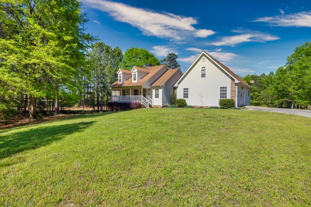 a view of a house next to a big yard and large trees