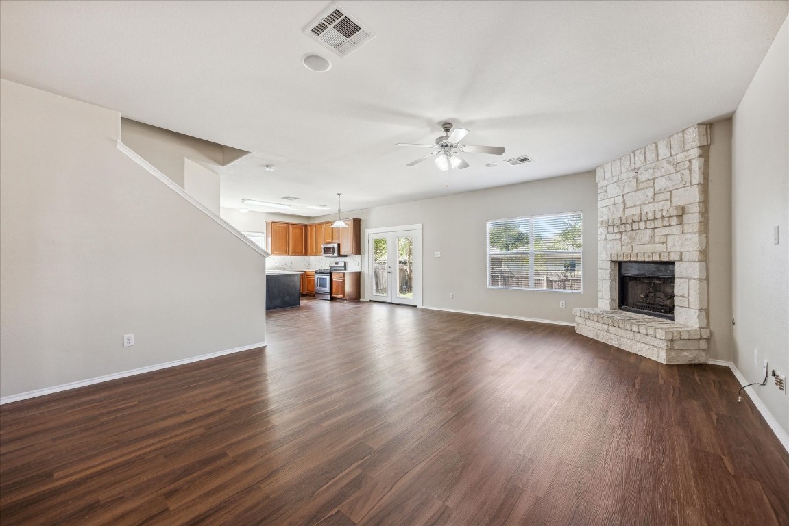 an empty room with wooden floor fireplace and windows