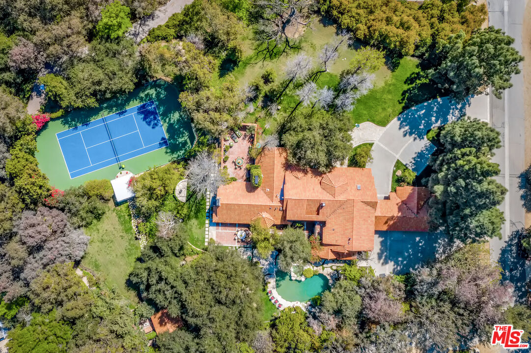 an aerial view of residential house with outdoor space and trees all around