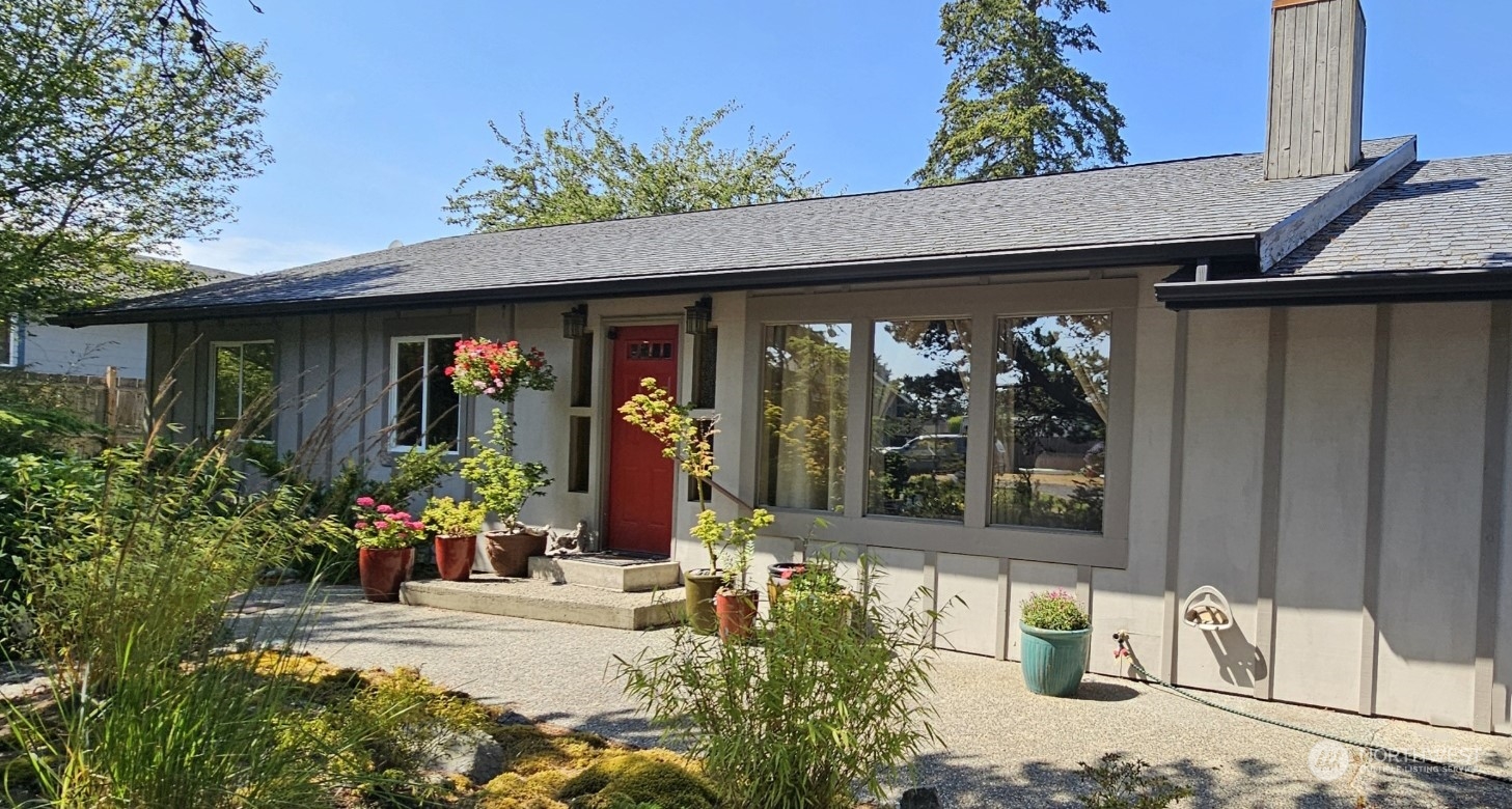 a front view of a house with lots of flowers planted