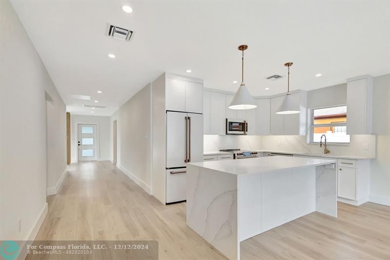 a kitchen with kitchen island a sink stainless steel appliances and cabinets