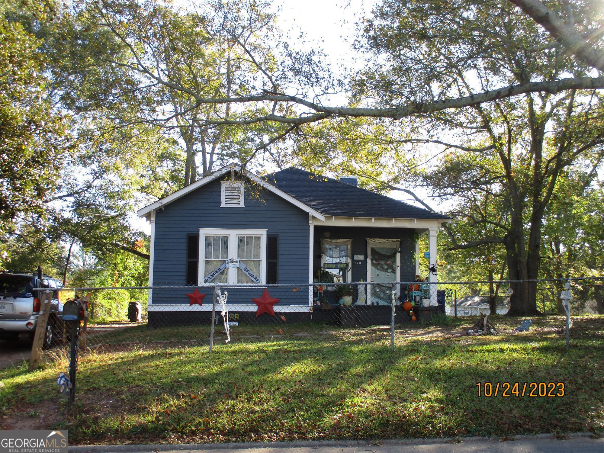 a view of a house with a yard potted plants and large tree