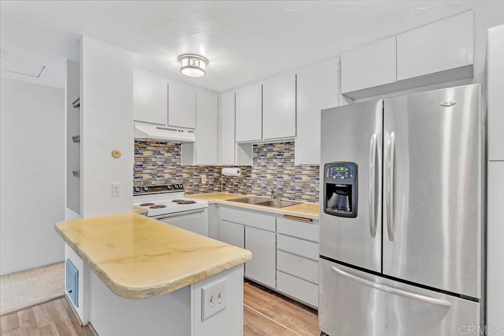 a kitchen with white cabinets and refrigerator