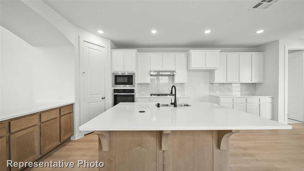 a kitchen with stainless steel appliances a sink a stove a refrigerator cabinets and a counter top space