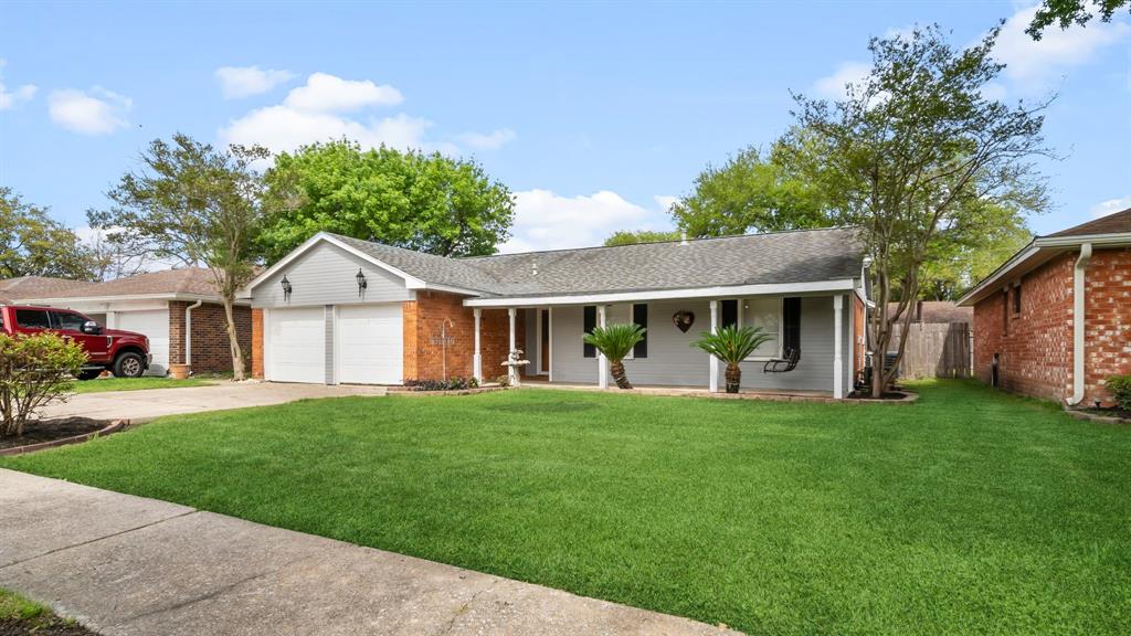 This is a single-story home with a well-maintained lawn, an attached two-car garage, and a covered porch. The exterior features a mix of brick and siding.