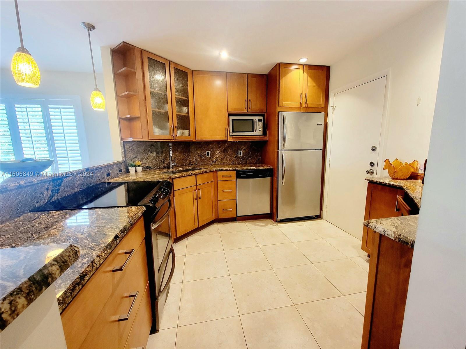 a kitchen with stainless steel appliances granite countertop a sink a stove a refrigerator a washer and dryer