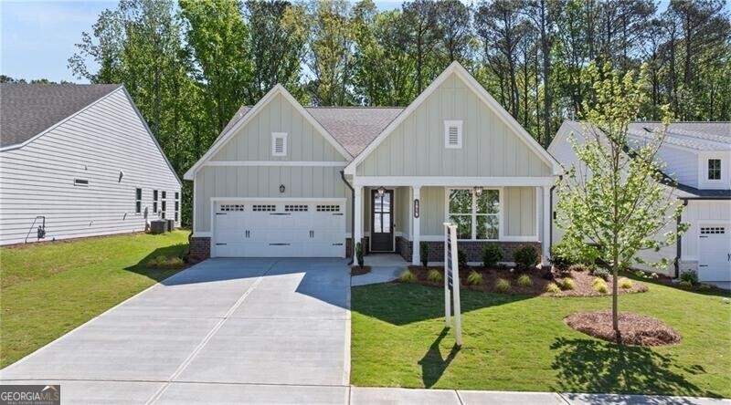 View of front of property featuring a garage, central AC, and a front lawn