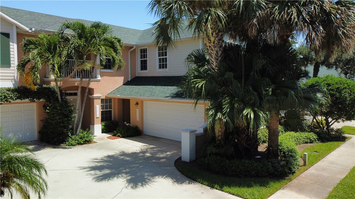 a view of a house with a yard and palm trees