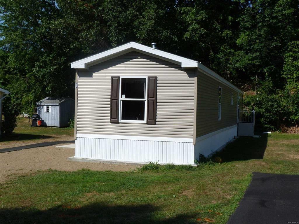 View of home's exterior with a yard and a storage shed