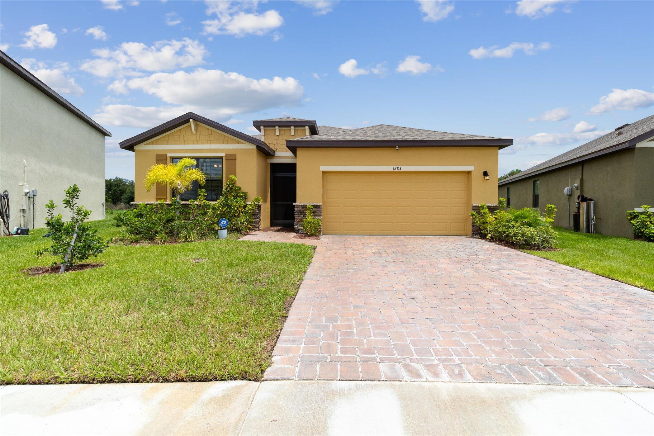 a view of yellow house with a yard and potted plants