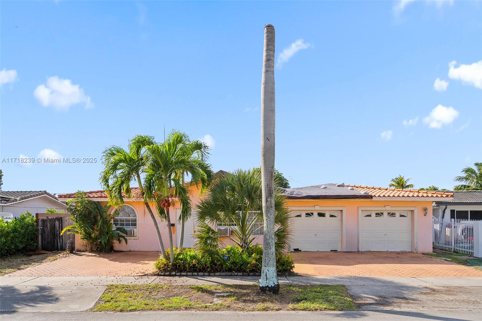 a front view of a house with a yard and palm trees