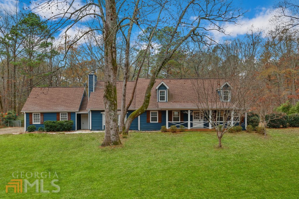 a front view of a house with garden and trees