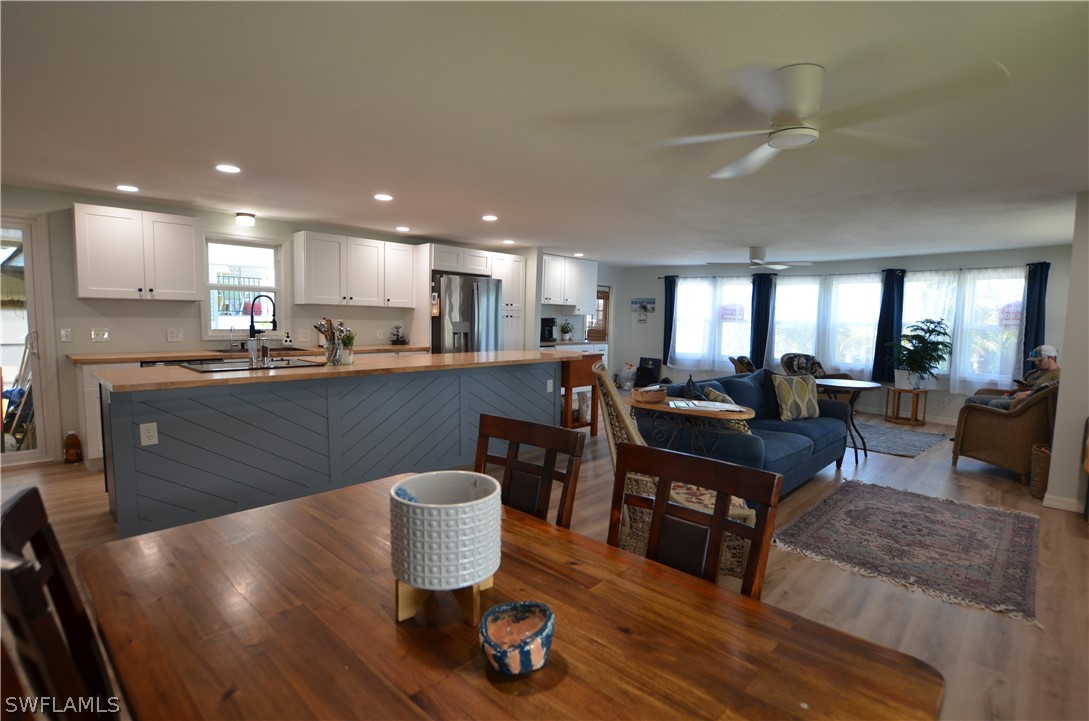 a living room with stainless steel appliances furniture a dining table and kitchen view