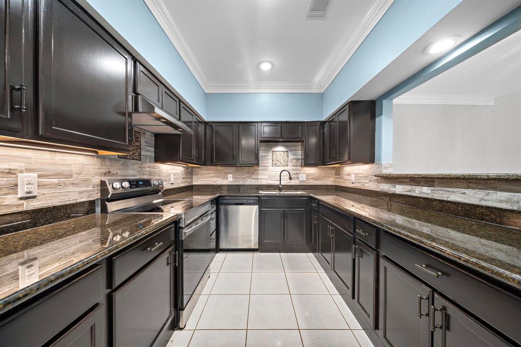 a kitchen with stainless steel appliances granite countertop a sink wooden cabinets and a stove top oven